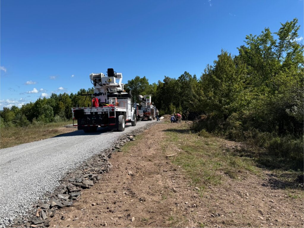 Power company trucks installing electricity lines on rural land, showing the process of bringing utilities to undeveloped property.